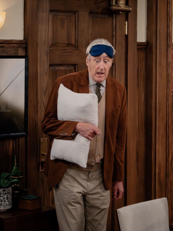 Alan wears a sleep mask and carries a pillow in Frasier