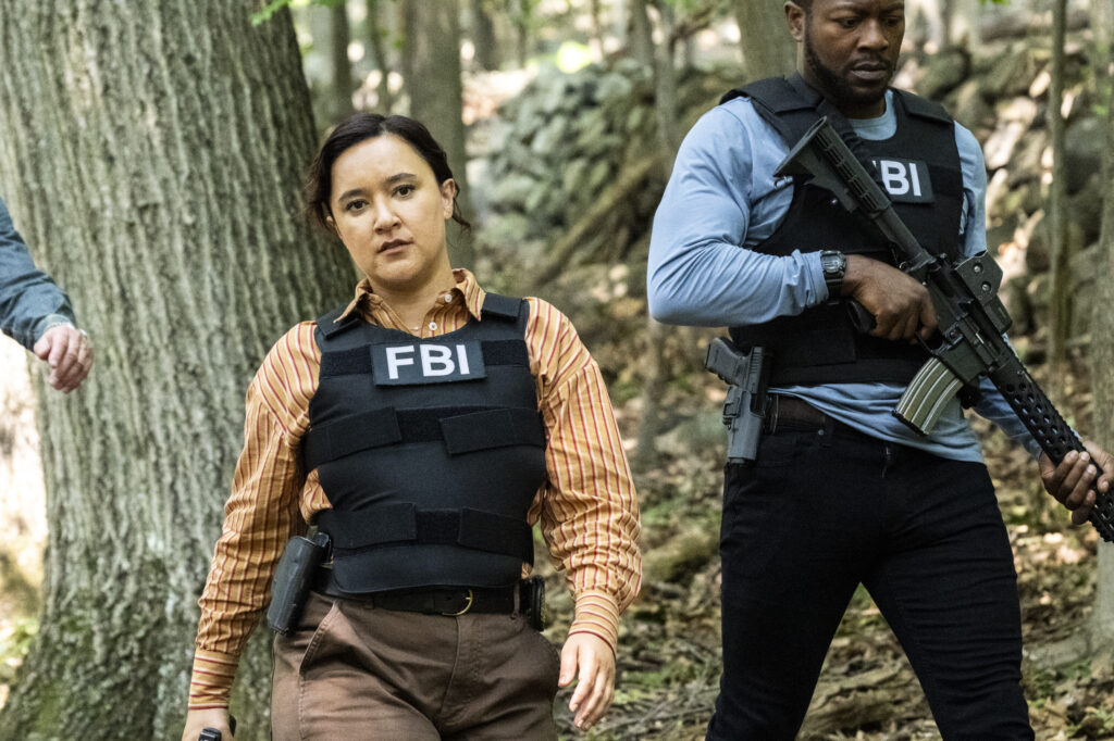 Hana and Ray walking through the woods with guns drawn on FBI: Most Wanted Season 6 Episode 3