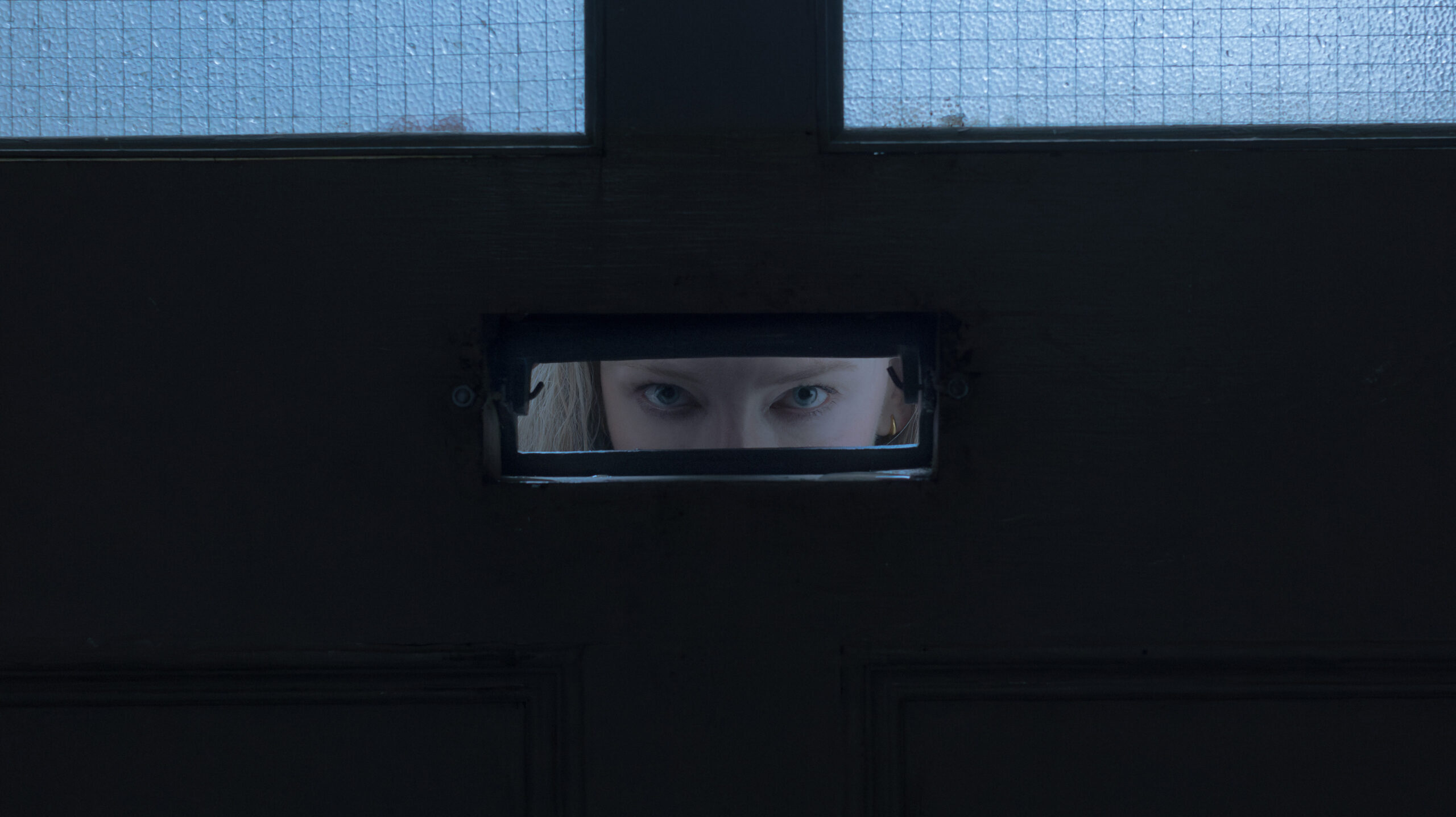 Catherine peeks through mail slot.