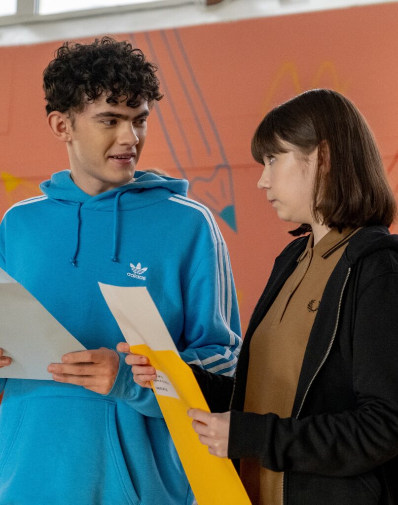 Tori and Charlie looking at each other while Tori opens her GCSE results on Heartstopper Season 3