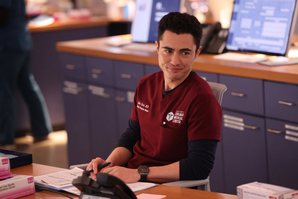 Frost sitting at his desk smiling on Chicago Med Season 10 Episode 22