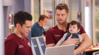 Frost and Ripley stand by the nurse's station on Chicago Med Season 10 Episode 21. Ripley is holding a baby.