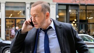 Danny standing on a busy street on the phone on Blue Bloods/Boston Blue
