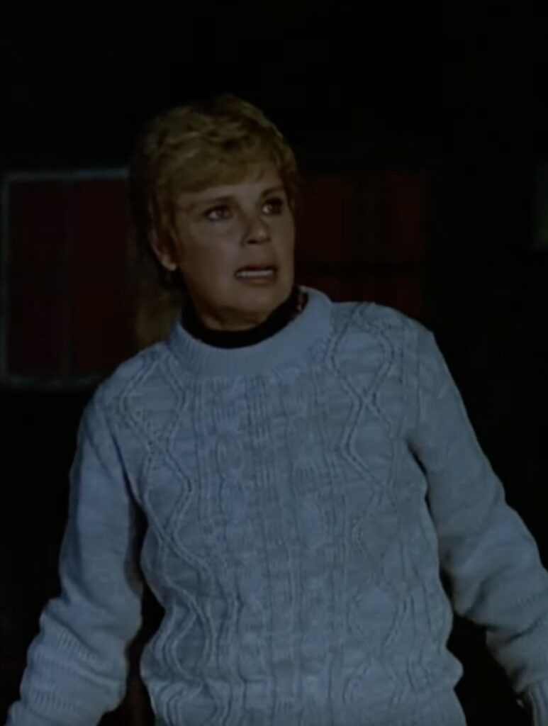 mrs vorhees in a gray cableknit sweater