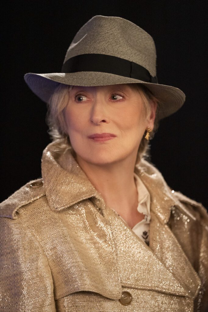 Loretta returns to New York with her stylish hat and trench coat on Only Murders In The Building Season 5 Episode 6