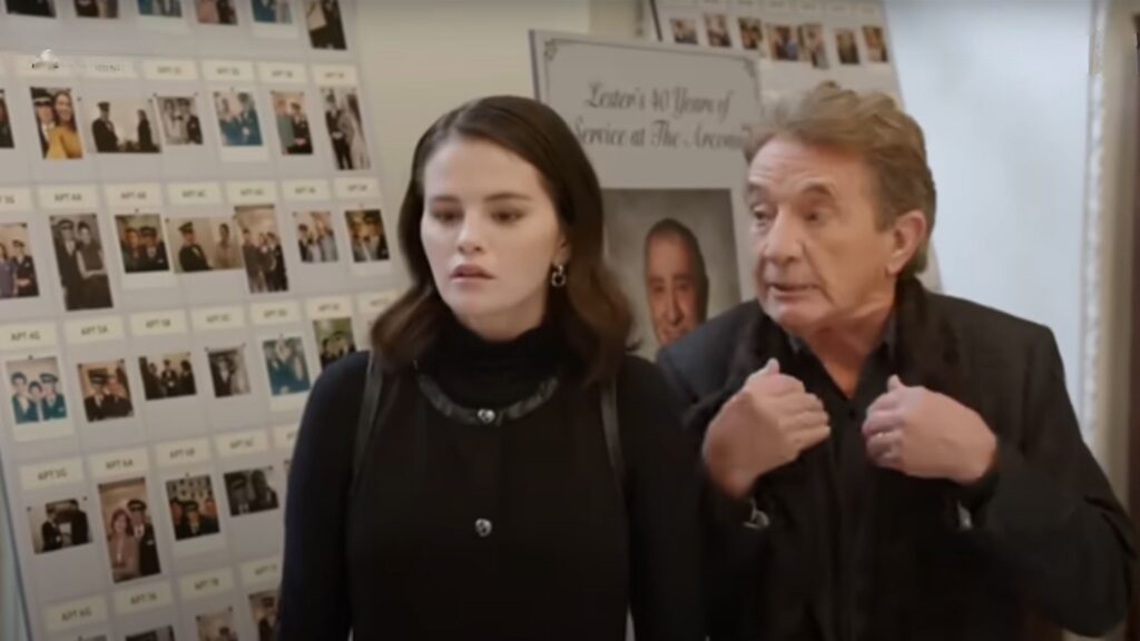 Mabel and Oliver standing by the memorial photos on Only Murders In The Building Season 5
