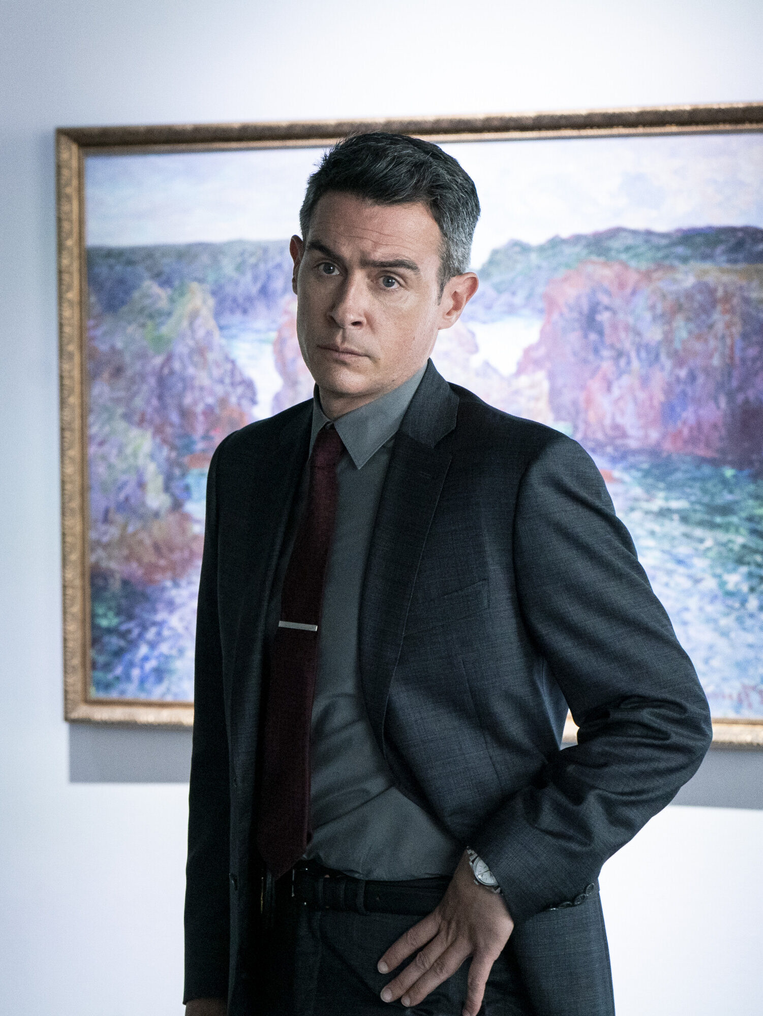 Scola standing in front of a painting on FBI Season 8 Episode 2