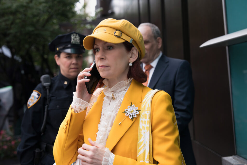 Elsbeth in yellow and on the phone on Elsbeth Season 3 Episode 3