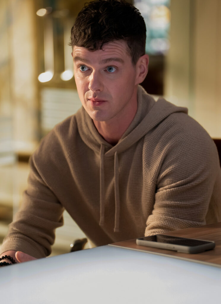 Adam seems very alert as he sits in on a meeting on Watson Season 2 Episode 5/