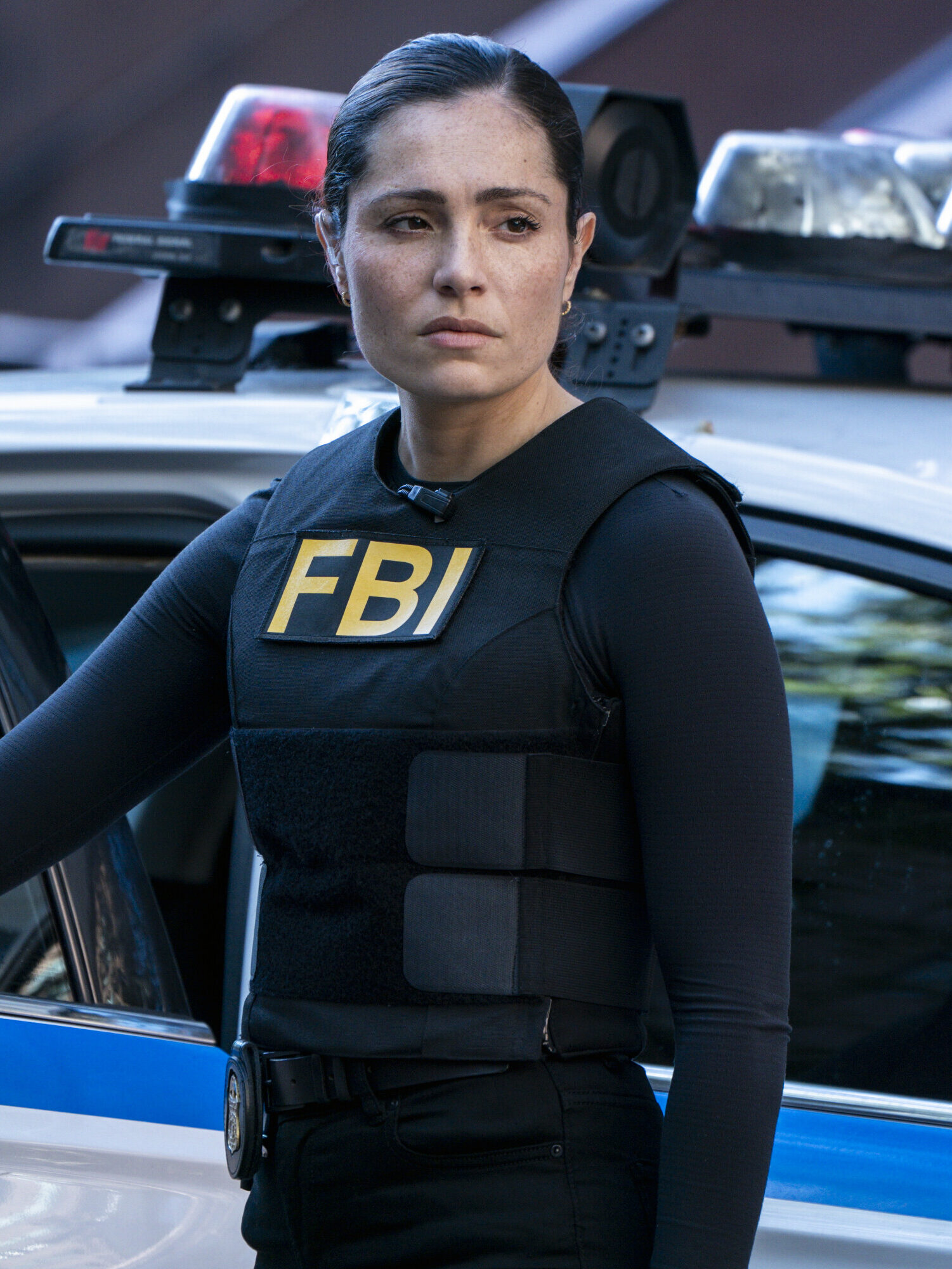 Ramos standing outside a police car looking determined on FBI Season 8 Episode 6