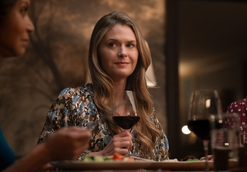 Sarah with a forced smile and a glass of wine on Boston Blue Season 1 Episode 8