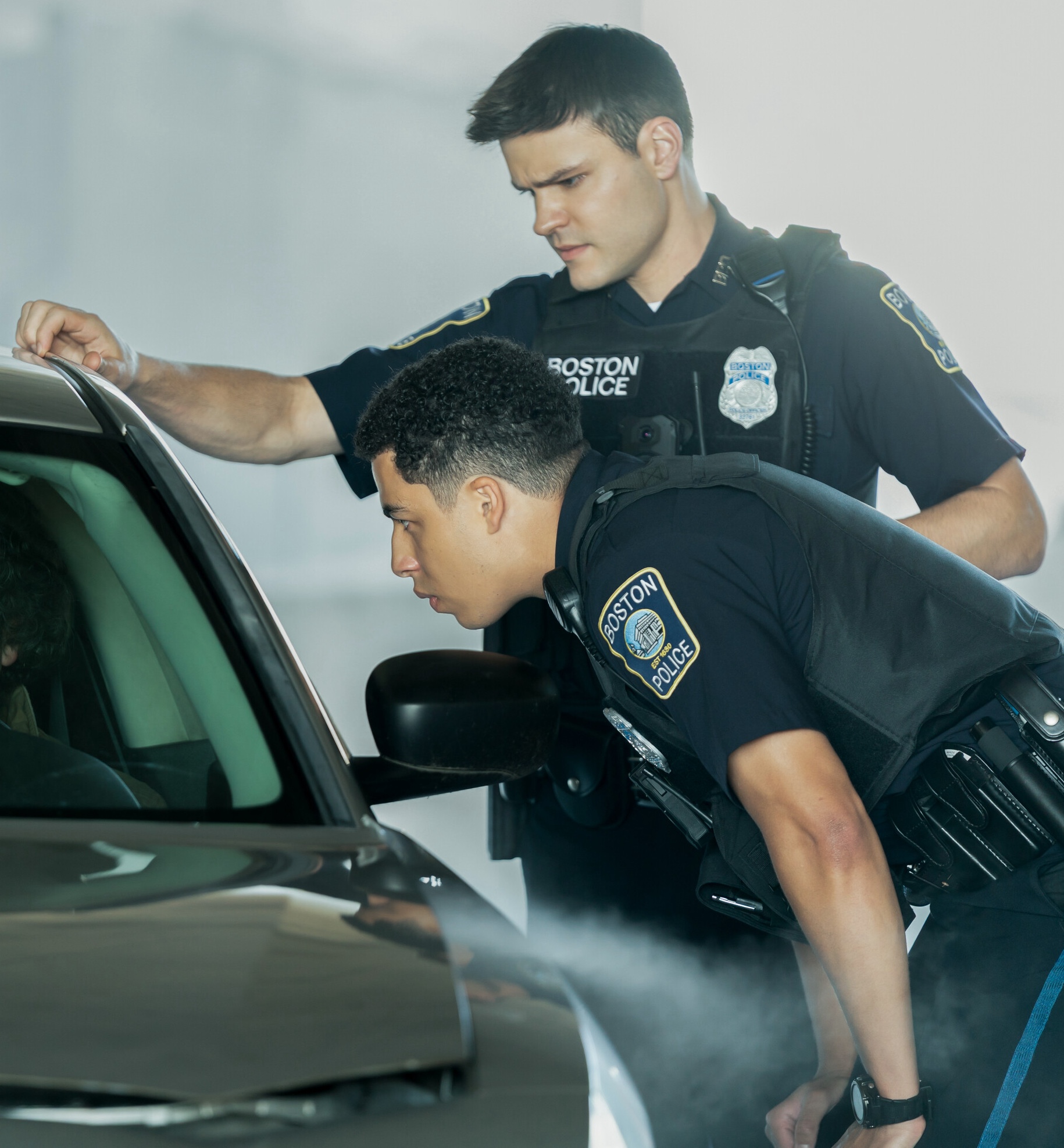 Sean and Jonah look through a car window at a suspect on Boston Blue Season 1 Episode 8