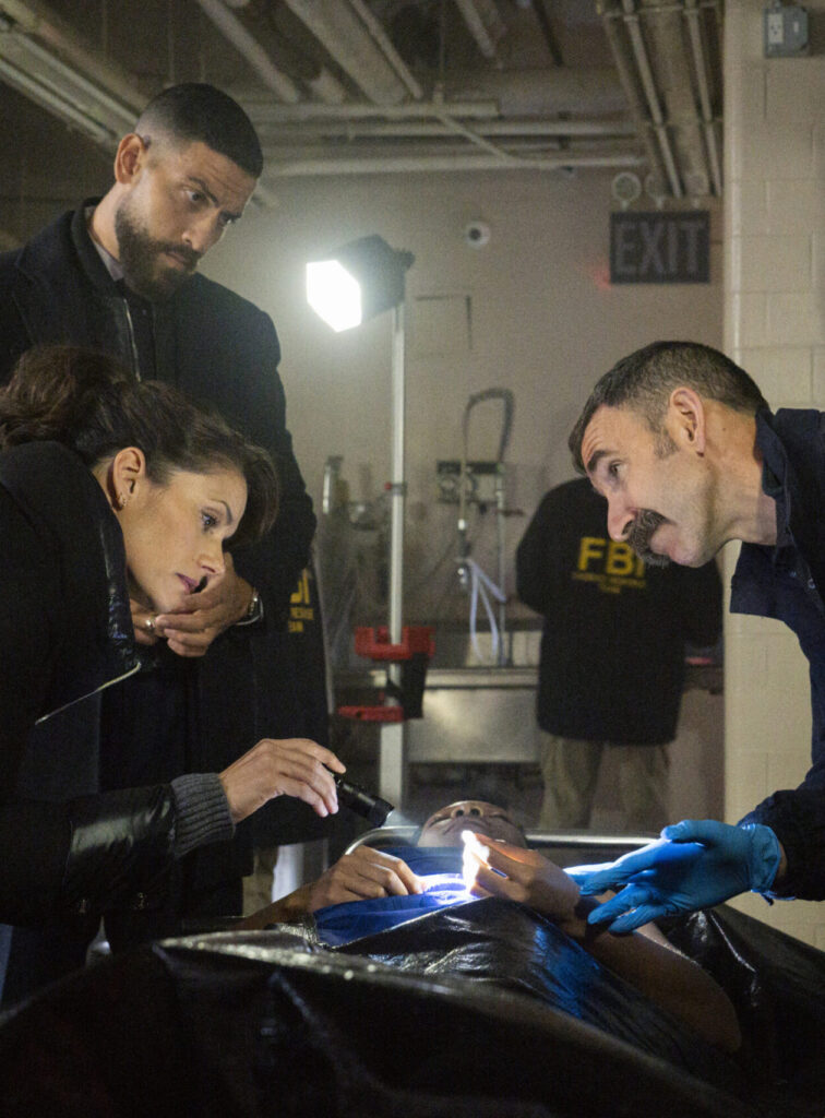 Maggie and OA examine a victim's body with the ME on FBI Season 8's Midseason Finale